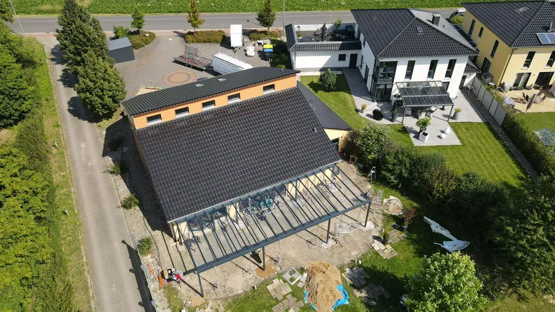 Drohnenblick auf die Montage eines großen Terrassendachs an einem Wohnhaus